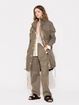Parka verde militar de gabardina con mangas largas, jareta en cintura, ruedo y cuello con cordón interno al tono. Acceso frontal con broches dorados. Bolsillos delanteros y laterales.