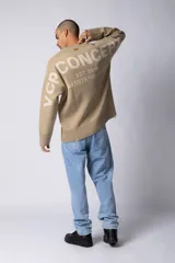 Sweater oversize de tejido de algodón color beige, con cuello redondo, puños y ruedo acanalados con detalles de desgaste. Presenta un diseño minimalista con etiqueta distintiva en el puño.