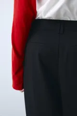Pantalón de tiro medio color beige, de corte ancho y recto, con pinzas frontales y trabillas en la cintura.