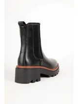 Bota tipo Chelsea de color negro, con elásticos laterales, suela track y taco cuadrado con detalle en tono marrón.