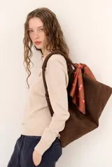 Sweater de punto color beige, de cuello redondo y manga larga, con detalle de pequeño bordado en el pecho.
