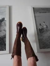 Botas altas de cuero color marrón oscuro combinadas con gamuza marrón, forradas en cuero y con cierre de bronce.