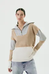 Sweater de lana color beige, gris y blanco, con cuello alto con cierre y detalles de crochet.