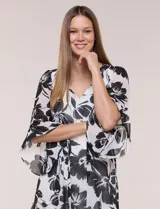Vestido corto de gasa semitraslúcida con estampado floral en blanco y negro, escote en V, mangas tres cuartos con volantes y lazo ajustable en la cintura.