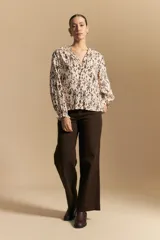 Camisa de manga larga con silueta relajada, estampado a rayas verticales en blanco y gris, escote abierto con botones frontales y puños elastizados.