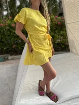 Vestido corto blanco de lino con corte evasé, mangas cortas con volados y cinto del mismo material.