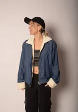 Campera azul de jean con interior de corderito blanco, cierre frontal y bolsillos laterales.