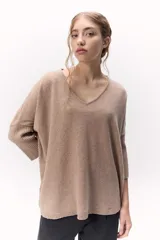 Sweater de tejido de punto color beige, con escote en V y calce holgado. Las mangas son tres cuartos con puños acanalados.