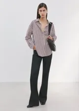 Camisa de corte recto confeccionada en mezcla de algodón y poliéster, con estampado de rayas. Cuenta con cuello camisero, manga larga con puños abotonados, bolsillo de parche en el pecho y cierre frontal con botones.