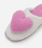 Pantufla abierta de diseño fluffy, confeccionada en poliéster suave de color blanco con una aplicación de corazón en relieve de color rosado. Cuenta con suela de goma termoplástica antideslizante y plantilla en tono rosado.