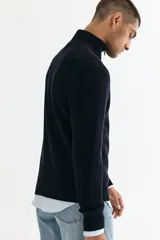 Buzo negro de tejido de punto suave, con cuello alto y medio cierre metálico. Presenta un corte estándar y manga larga con puños y bajo rectos.