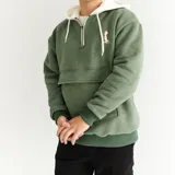 Canguro verde seco con capucha y cordones blancos, cierre parcial con cremallera, bolsillo tipo canguro y logo bordado en el pecho.