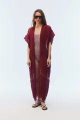 Kimono largo de punto calado color bordó, de diseño abierto al frente con hombros caídos, mangas cortas, aberturas laterales y terminación desflecada en el ruedo.
