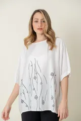 Blusa blanca de viscosa con estampado de flores negras, de corte holgado, cuello redondo y mangas cortas.
