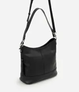 Cartera hobo grande de cuero negro con asa ajustable, cierre superior, detalle de tassel lateral y aplicaciones metálicas plateadas.
