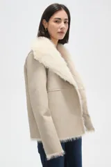 Chaqueta de eco-cuero negro con interior y cuello de piel sintética, diseño holgado, manga larga y cierre frontal con un botón.