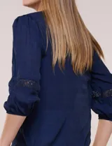 Blusa blanca de bambula con escote en V, pechera de encaje y mangas 3/4 abullonadas con detalles de puntilla.