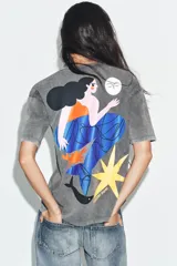 Camiseta de corte oversize con efecto lavado, cuello redondo y manga corta. Presenta un estampado pequeño a contraste en el pecho que representa una figura femenina con una estrella.