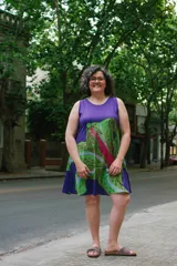 Vestido corto sin mangas con estampado de una flor de lirio verde y fucsia sobre fondo violeta.