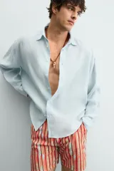Camisa de corte relajado confeccionada en tejido de lino, con cuello solapa, manga larga con puños abotonados y cierre frontal de botones.