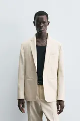 Blazer de corte regular fit confeccionado en tejido con lana. Presenta cuello con solapas de muesca, cierre frontal de un botón, bolsillos de vivo en el pecho y en la cadera, y aberturas en la espalda.