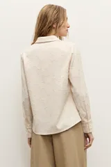 Camisa de manga larga color beige con diseño texturizado en tono sobre tono, cuello clásico y cierre frontal con botones.