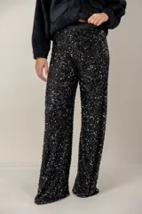 Pantalón de corte recto y tiro alto, completamente cubierto de lentejuelas negras brillantes. Cuenta con una cintura elástica de tela lisa para mayor comodidad.