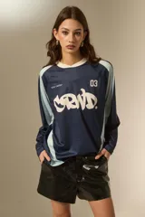 Remera de manga larga estilo deportivo, confeccionada en tejido técnico. Presenta un diseño color block en tonos bordó y rosa, con cuello mao y estampado gráfico frontal en color blanco.