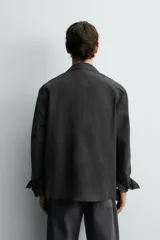 Blazer cruzado de corte relajado, confeccionado en mezcla de algodón y lino, en color gris oscuro. Presenta solapas de pico, bolsillos de parche en la cadera y cierre frontal de doble botonadura.