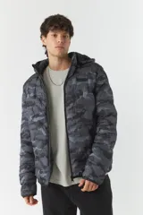Campera puffer de nylon con estampado camuflado en tonos grises y negros. Tiene capucha desmontable, cuello medio y bolsillos con cierre. El modelo usa talle M.