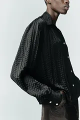 Camisa de manga larga con cuello solapa, confeccionada en tejido satinado con textura efecto arrugado y cierre frontal con botones.