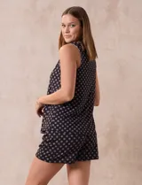 Conjunto de pijama de dos piezas, compuesto por una musculosa sin mangas con escote en V y botones frontales, y un short. Ambas prendas son de tejido soft estampado en color negro con diseño de pequeños círculos claros.