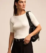 Blusa de punto color blanco, con textura acanalada, cuello redondo y mangas cortas. Presenta un corte oval en la espalda.