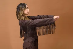 Campera de cuero marrón oscuro con diseño de flecos largos en el frente y las mangas. Presenta un corte recto, cierre frontal con cremallera y cuello clásico, con un estilo inspirado en la estética western.