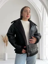 Campera negra de cuero sintético con interior de piel sintética color negro, corte oversize, cuello solapa y cierre frontal con cremallera.