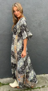 Vestido largo cruzado al frente, con escote en V, mangas fluidas 3/4 y elástico en la espalda. Confeccionado en seda con estampado geométrico y detalles bordados en el escote.