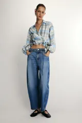Jeans de tiro medio con diseño barrel, cinco bolsillos y cinturón fino del mismo tejido. Presenta pernera ancha en los muslos que se estrecha gradualmente hacia el tobillo, con cierre frontal de cremallera y botón.