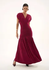 Vestido largo color bordó con escote en V, cuerpo ajustado con detalle de drapeado central y falda fluida con caída amplia.
