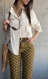 Camisa de manga larga color marfil con detalles de encaje y botones frontales.