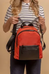 Mochila urbana de diseño combinado, confeccionada en tela resistente con bolsillo frontal y detalles en cuero sintético. Cuenta con compartimento principal con cierre y correas ajustables.