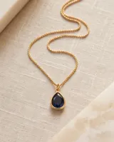 Collar de cadena fina en color dorado con un dije colgante en forma de gota con piedra negra de onix.