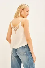 Top tipo musculosa de modal satén color crema, con detalle de encaje calado y bordados a tono en el escote delantero y en la espalda.