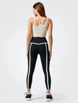 Top deportivo color blanco con diseño asimétrico de aberturas ovaladas en el escote, confeccionado en tejido con tecnología Aloe Vera.