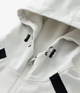 Campera deportiva con capucha, color blanco con recortes laterales en negro. Cuenta con cierre frontal, bolsillos funcionales y ajuste en la cintura.