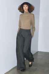 Pantalón wide leg gris oscuro con raya diplomática, tiro medio, bolsillos laterales ocultos, pinzas delanteras y cierre frontal con cremallera, botón y ganchos metálicos.