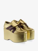 Zapatilla deportiva con plataforma extragrande, color plateado metálico con efecto arrugado en la plataforma y acabado brillante en el cuerpo. Presenta tres franjas laterales en azul marino brillante y cordones azules.