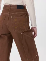 Pantalón de tiro medio y pierna ancha confeccionado en denim de algodón grueso. Presenta un diseño a rayas verticales en tonos azul y celeste, con costuras en contraste color rojo, bolsillos laterales tipo cargo y remaches metálicos.