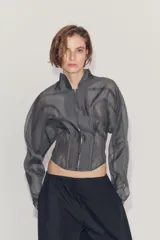 Corset tipo bomber de la colección Zara Woman, confeccionado en hilatura con mezcla de viscosa transparente, con cuello subido, manga larga y varillas interiores que definen la estructura. Cuenta con cierre frontal mediante ganchos metálicos.