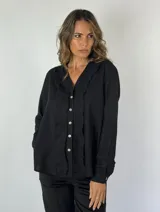 Camisa color mostaza con volados desflecados a lo largo de la botonadura frontal, cuello mao y mangas largas con puños abotonados.