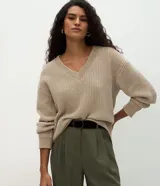 Suéter de punto color beige con escote en V, mangas largas con puños ajustados y diseño holgado. Confeccionado en poliéster.
